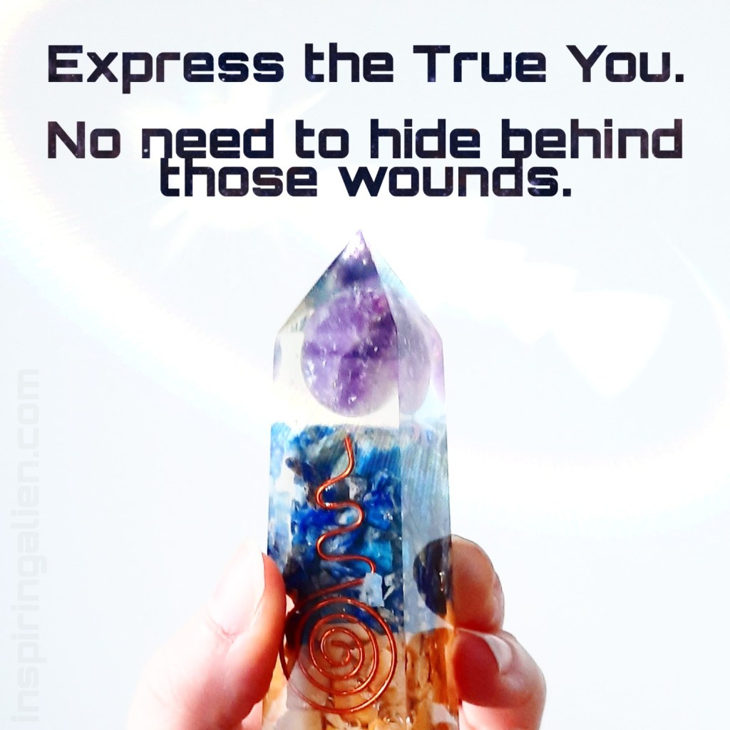 fingers holding orgonite obelisk that has an amethyst sphere, lapis lazuli chips and yellow aventurine chips, with a copper spiral that goes into a wavy shape upward.
Text saying: Express the True You. No need to hide behind those wounds.